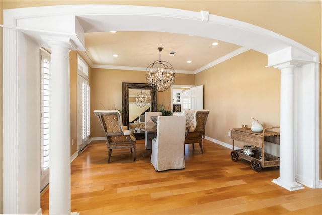 dining space with crown molding, decorative columns, and light wood-style floors