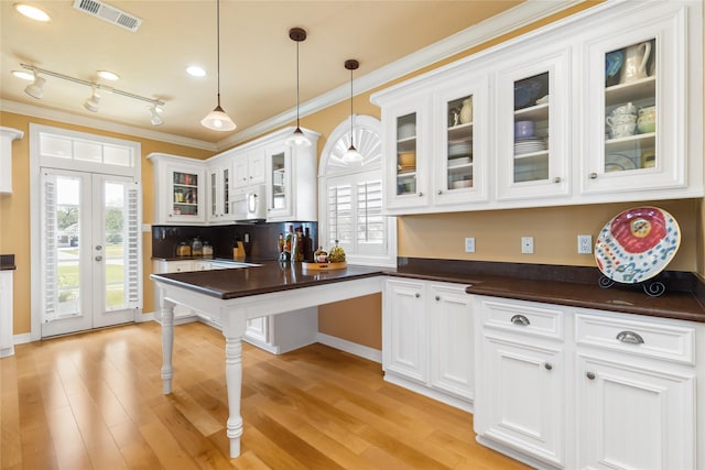 kitchen with ornamental molding, white microwave, dark countertops, white cabinets, and visible vents