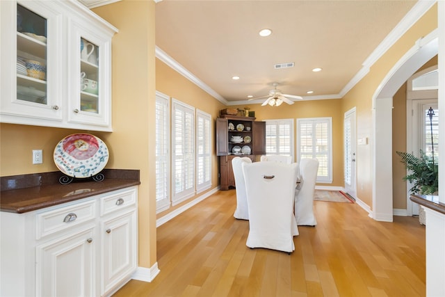 dining space featuring visible vents, arched walkways, ornamental molding, recessed lighting, and light wood-style flooring