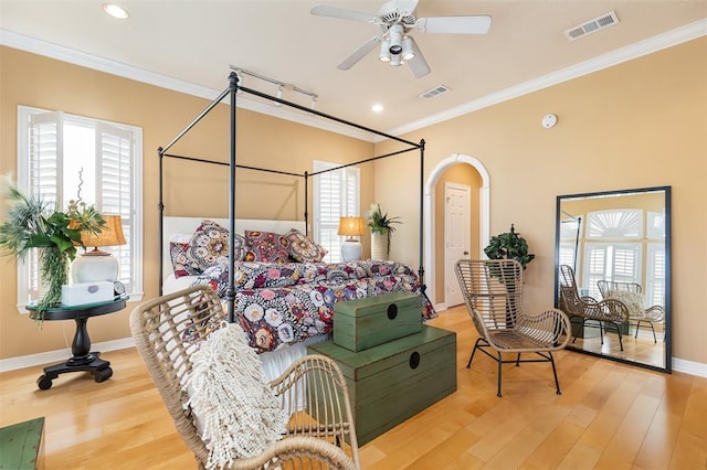 bedroom featuring arched walkways, ornamental molding, visible vents, and light wood-type flooring