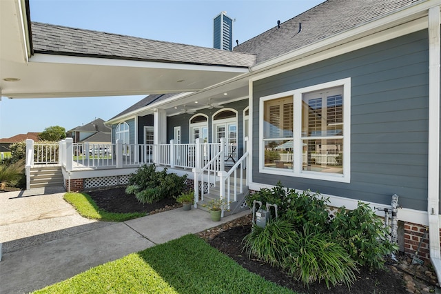 entrance to property featuring a porch, a chimney, and a shingled roof