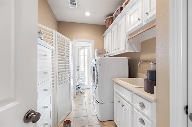 laundry area with light tile patterned floors, visible vents, cabinet space, washer and dryer, and a sink