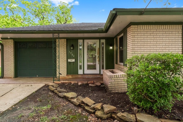 1702 Sheridan Dr, Baytown, TX 77520 - doorway to property featuring brick siding, driveway, a garage, and roof with shingles