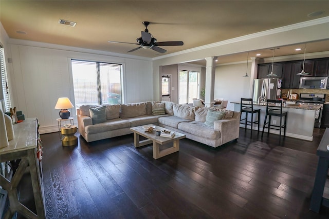 living room with dark wood-style flooring, a ceiling fan, ornate columns, and ornamental molding