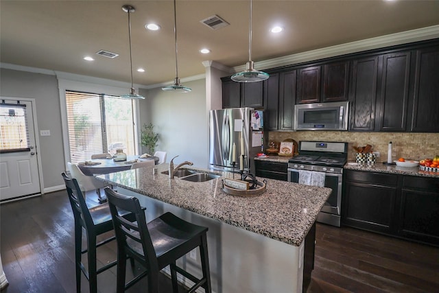 kitchen with a sink, decorative backsplash, appliances with stainless steel finishes, ornamental molding, and visible vents