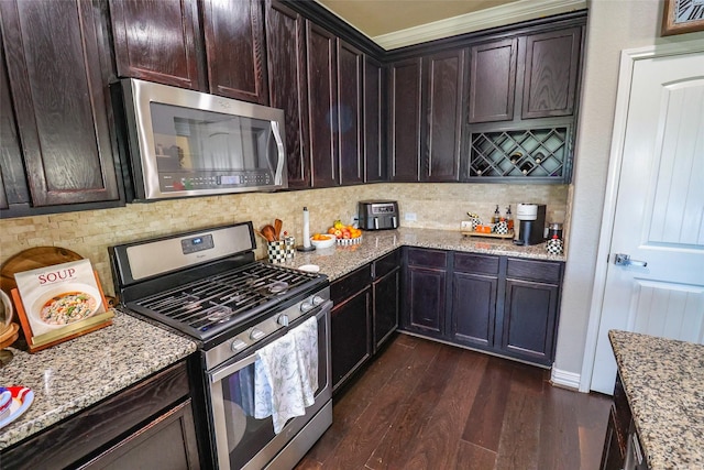 kitchen with tasteful backsplash, dark brown cabinets, appliances with stainless steel finishes, dark wood-style flooring, and light stone countertops