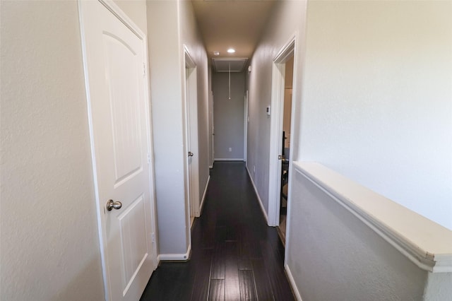 hallway with attic access, baseboards, and dark wood-style flooring