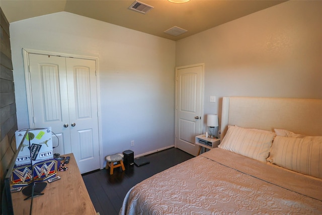 bedroom with a closet, lofted ceiling, visible vents, and dark wood-style floors