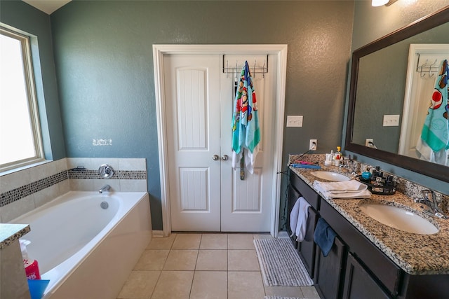 bathroom featuring a garden tub, a textured wall, tile patterned flooring, and a sink