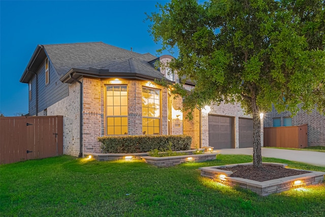 view of front of home featuring driveway, fence, a front lawn, and brick siding