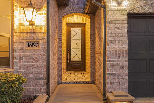 entrance to property featuring brick siding and an attached garage