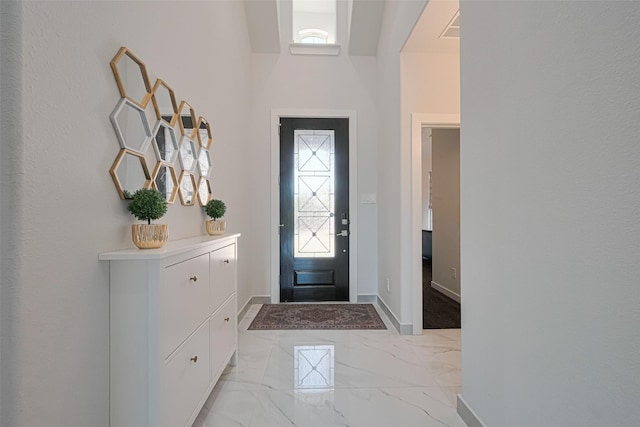 foyer entrance with marble finish floor and baseboards