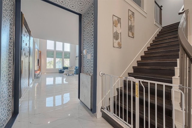 stairway with baseboards, marble finish floor, and a high ceiling