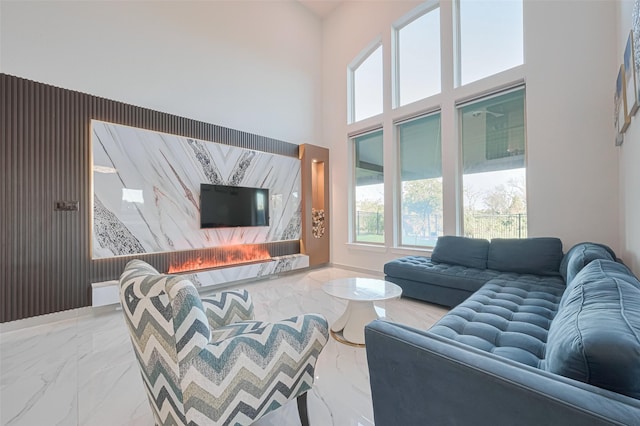 living area featuring a premium fireplace, a towering ceiling, and marble finish floor