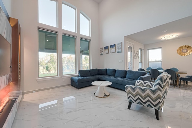 living room featuring a high ceiling, marble finish floor, and baseboards