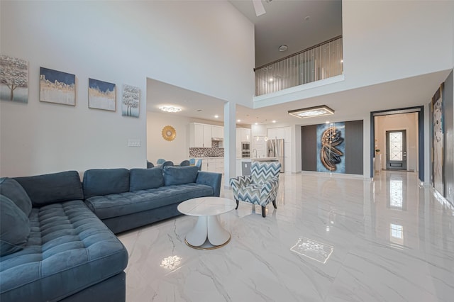 living area featuring a towering ceiling and marble finish floor