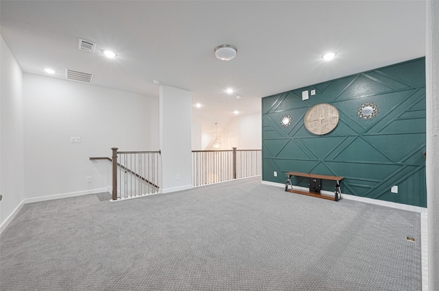interior space with carpet flooring, visible vents, an upstairs landing, and baseboards