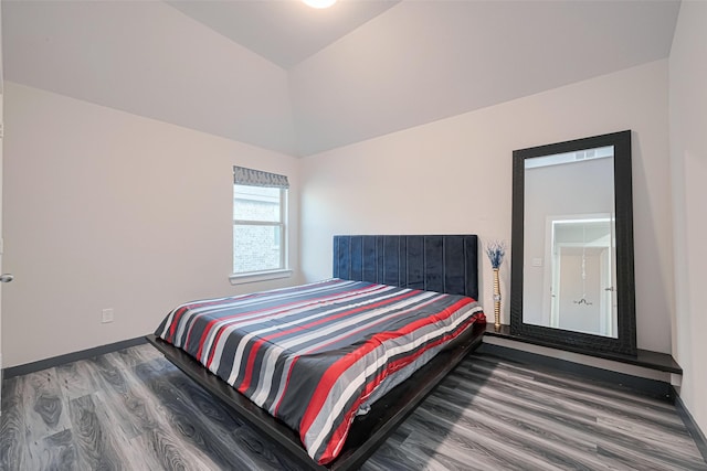 bedroom featuring baseboards, vaulted ceiling, and wood finished floors