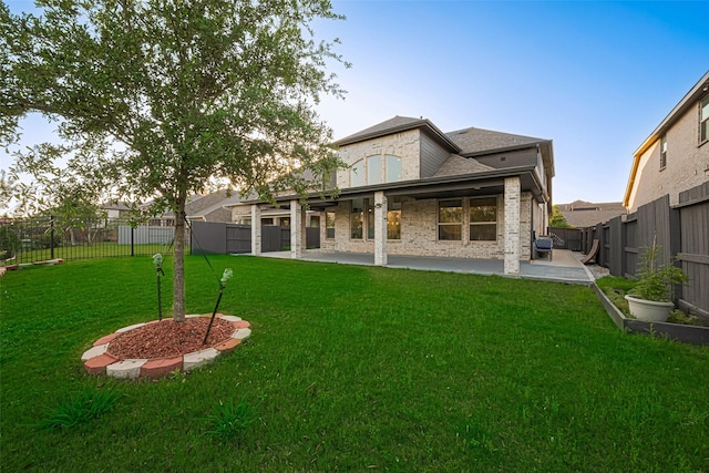 back of house featuring a patio, brick siding, a fenced backyard, a yard, and a shingled roof
