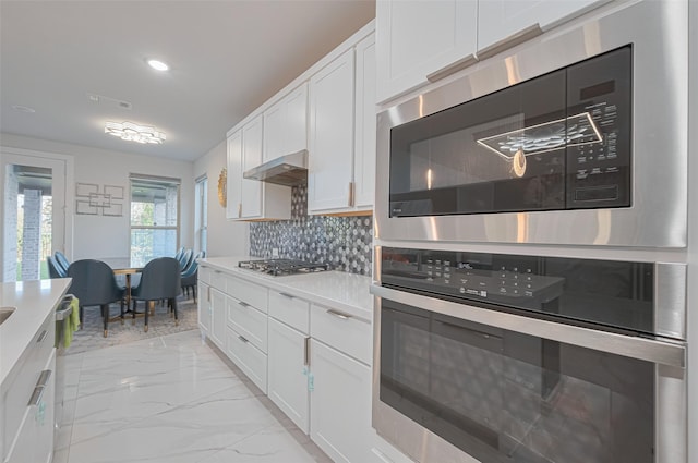 kitchen with white cabinetry, light countertops, appliances with stainless steel finishes, and marble finish floor