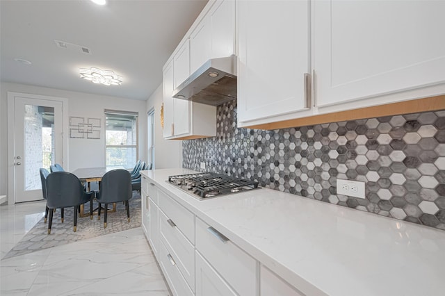 kitchen with marble finish floor, wall chimney exhaust hood, white cabinetry, and stainless steel gas stovetop
