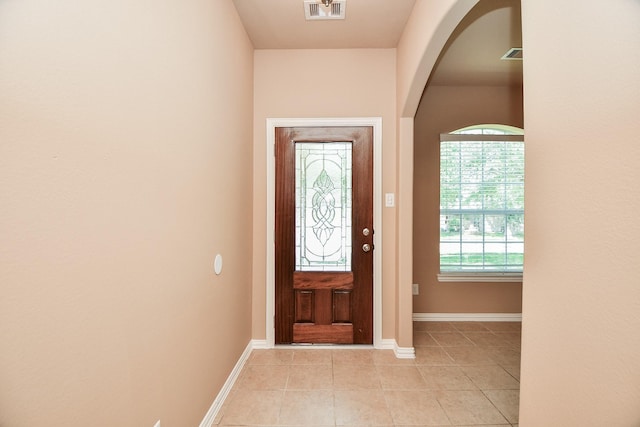foyer featuring baseboards, visible vents, arched walkways, and light tile patterned floors