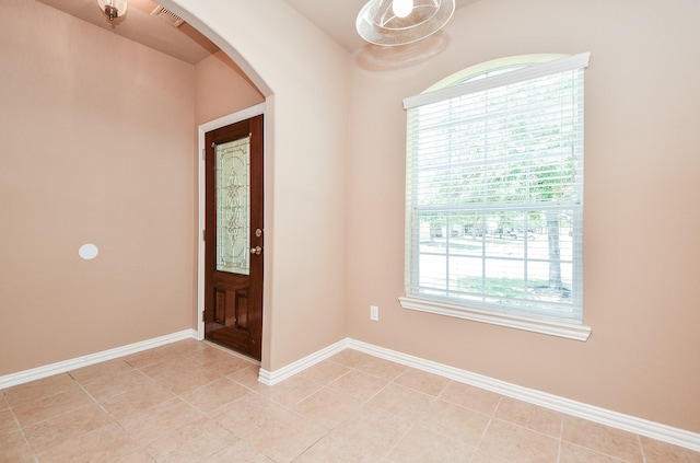 foyer entrance featuring baseboards, visible vents, arched walkways, and light tile patterned floors