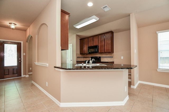 kitchen featuring black microwave, dark stone countertops, a sink, and visible vents