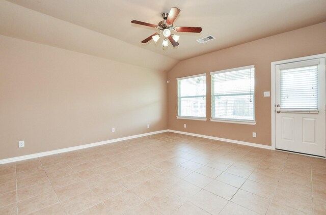 empty room with lofted ceiling, visible vents, light tile patterned floors, baseboards, and ceiling fan