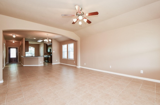 unfurnished living room featuring arched walkways, plenty of natural light, and baseboards