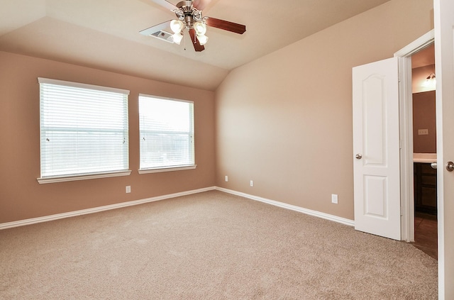 carpeted spare room with lofted ceiling, a ceiling fan, baseboards, and visible vents
