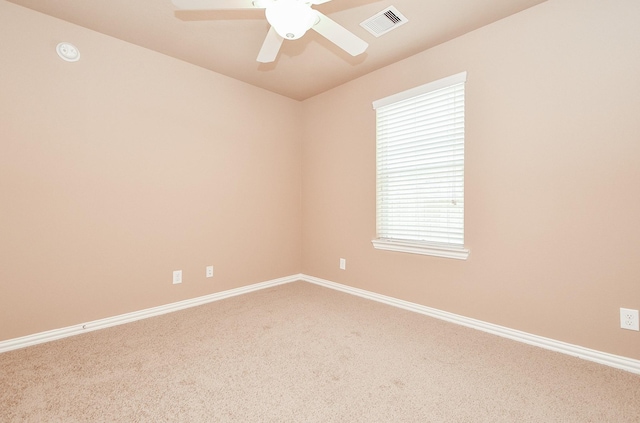 carpeted spare room with baseboards, a ceiling fan, and visible vents