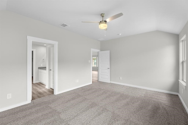 unfurnished bedroom with ensuite bathroom, visible vents, vaulted ceiling, carpet floors, and baseboards