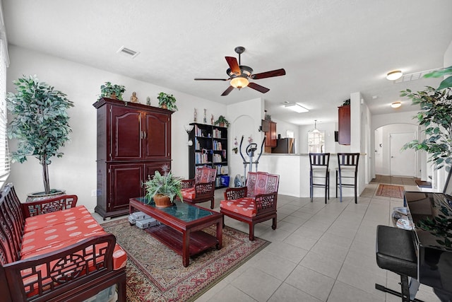living room with arched walkways, light tile patterned floors, a ceiling fan, and visible vents