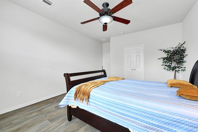 bedroom featuring visible vents, baseboards, ceiling fan, and wood finished floors