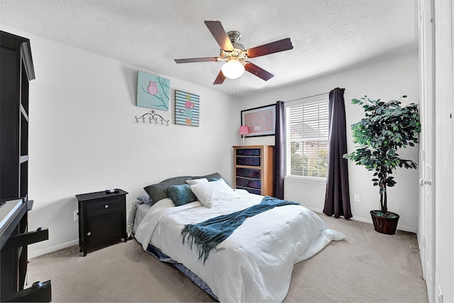 bedroom with baseboards, a ceiling fan, light colored carpet, and a textured ceiling