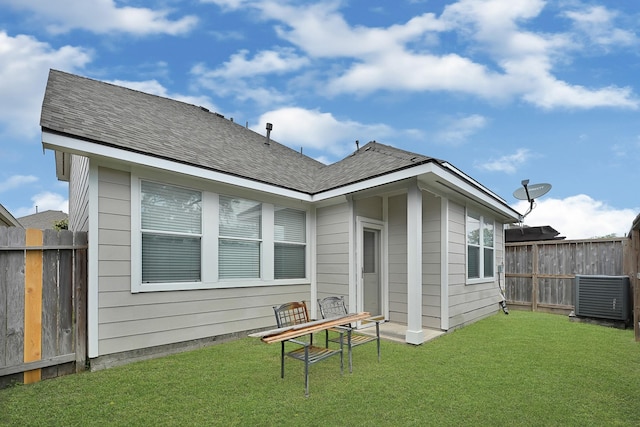back of property featuring cooling unit, fence, and a lawn
