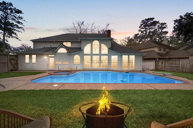 14102 Haynes Dr, Houston, TX 77069 - pool at dusk with a diving board, fence, a fire pit, and a lawn