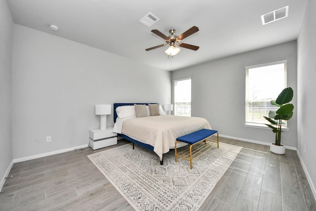 bedroom with visible vents, baseboards, ceiling fan, and wood finished floors