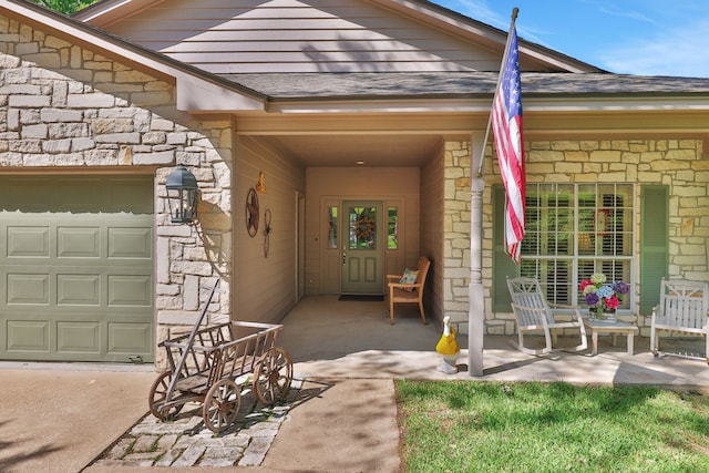 doorway to property with an attached garage, a porch, a shingled roof, and stone siding