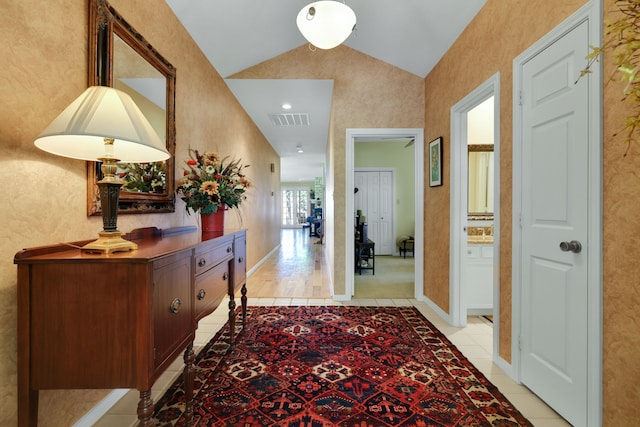corridor with light tile patterned flooring, vaulted ceiling, and visible vents