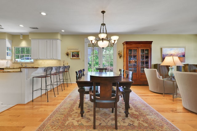 dining area with light wood finished floors, a notable chandelier, visible vents, and recessed lighting