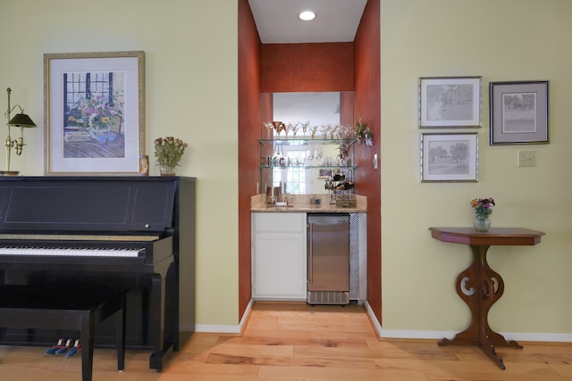 bar with baseboards, light wood-type flooring, wet bar, recessed lighting, and refrigerator