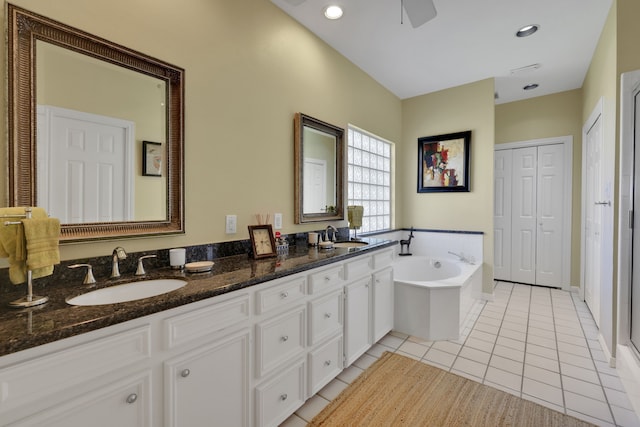 bathroom featuring a sink, a closet, tile patterned flooring, and a garden tub