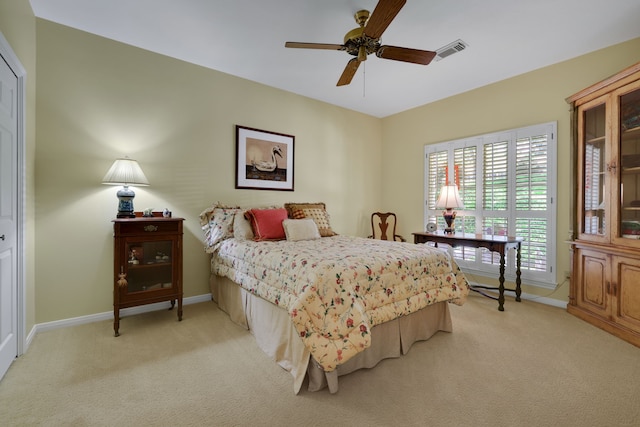 bedroom featuring light carpet, visible vents, baseboards, and a ceiling fan