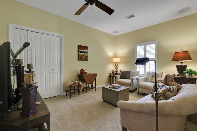 living room featuring light carpet, visible vents, baseboards, and a ceiling fan