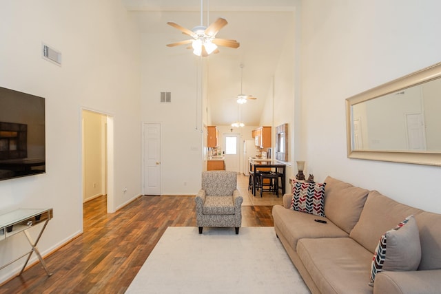 living room featuring baseboards, dark wood-style floors, a ceiling fan, visible vents, and high vaulted ceiling