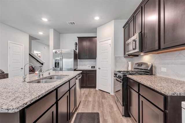 21723 Sarasota Spice St, Tomball, TX 77377 - kitchen featuring visible vents, a sink, appliances with stainless steel finishes, dark brown cabinetry, and light wood finished floors