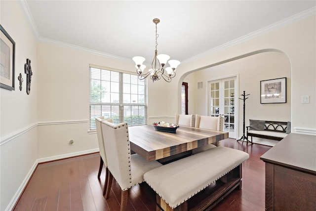 dining space with arched walkways, crown molding, and dark wood finished floors
