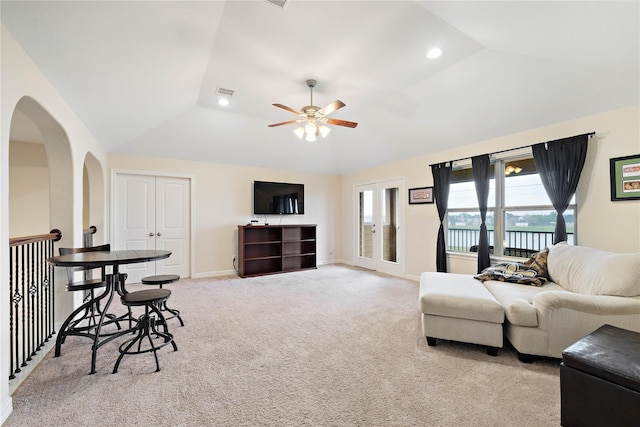 living area featuring visible vents, arched walkways, a ceiling fan, vaulted ceiling, and light carpet